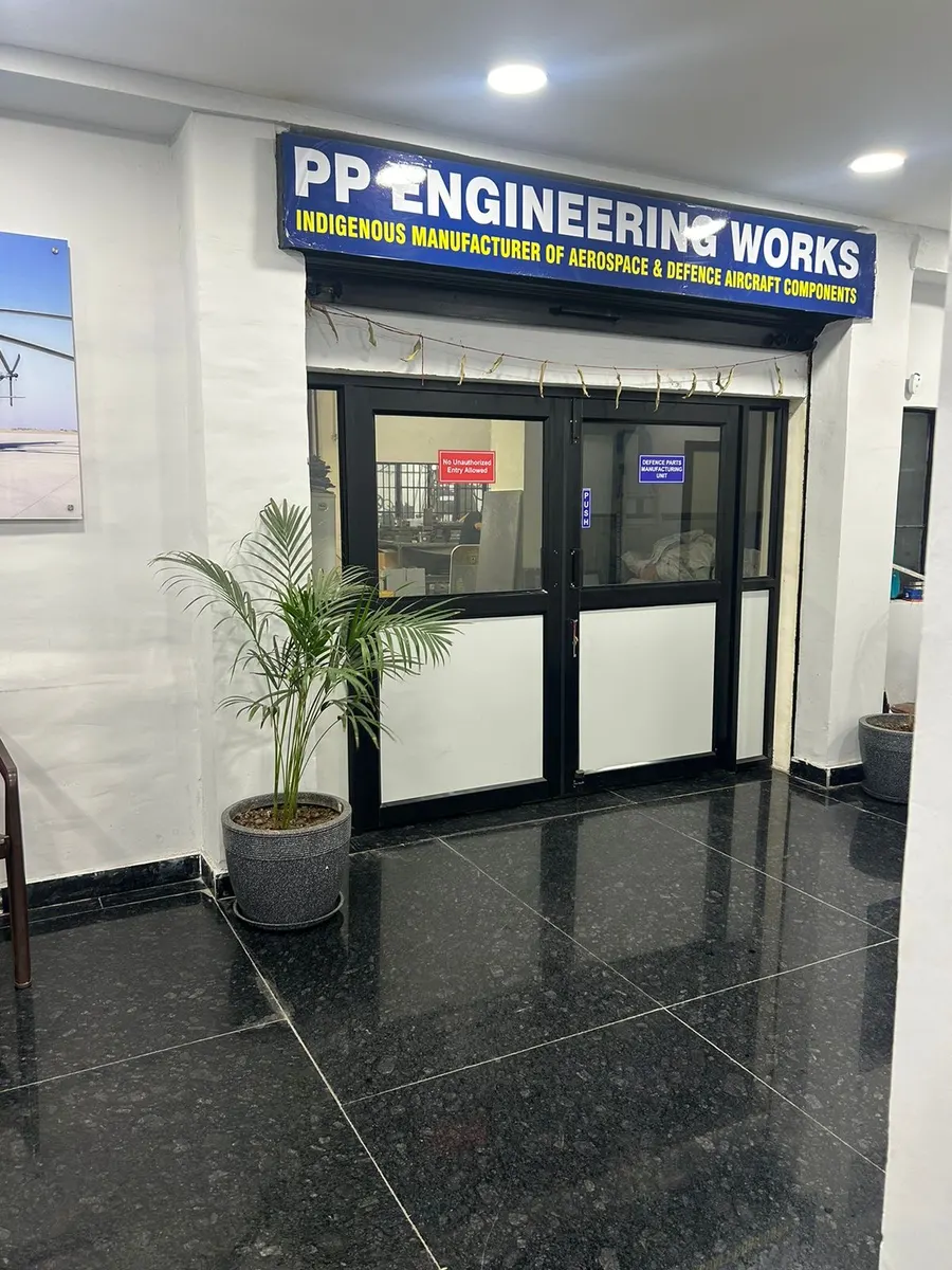 Glass entrance doors below a blue signboard, with notices reading Defence Parts Manufacturing Unit and No Unauthorized Entry Allowed.